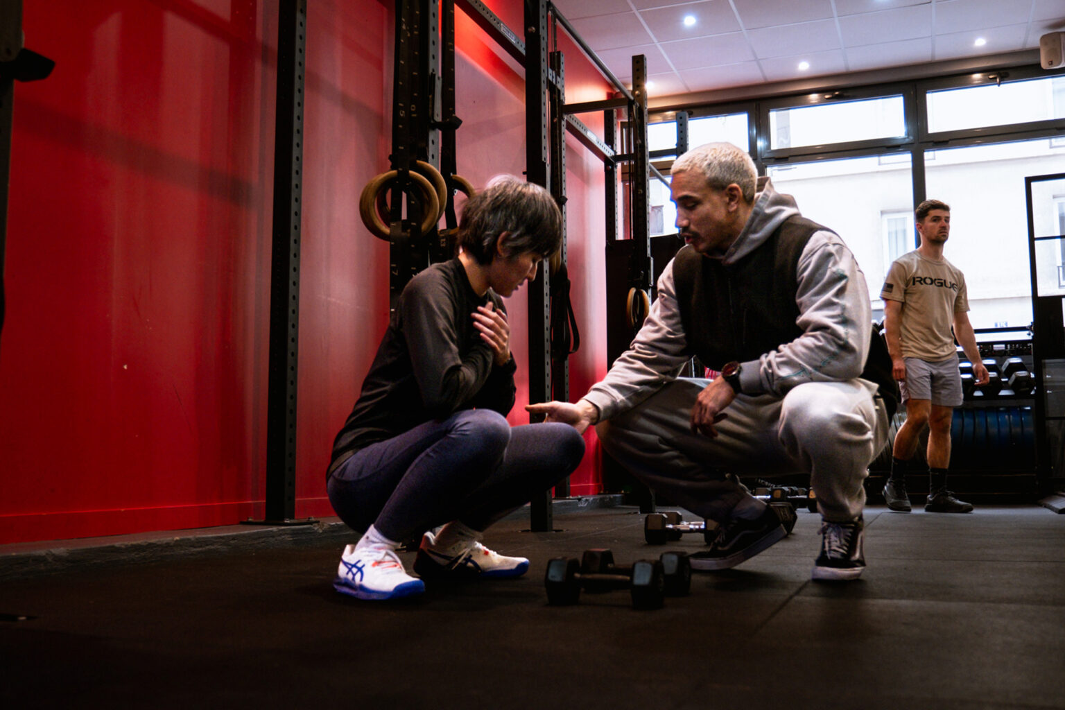 Coach en train de montrer des points techniques sur le mouvement du squat à une adhérente débutante